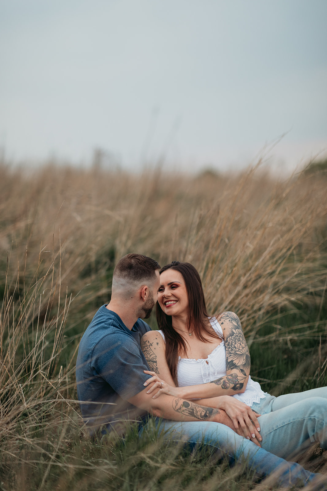 couple sitting in an open field on a cloudy day